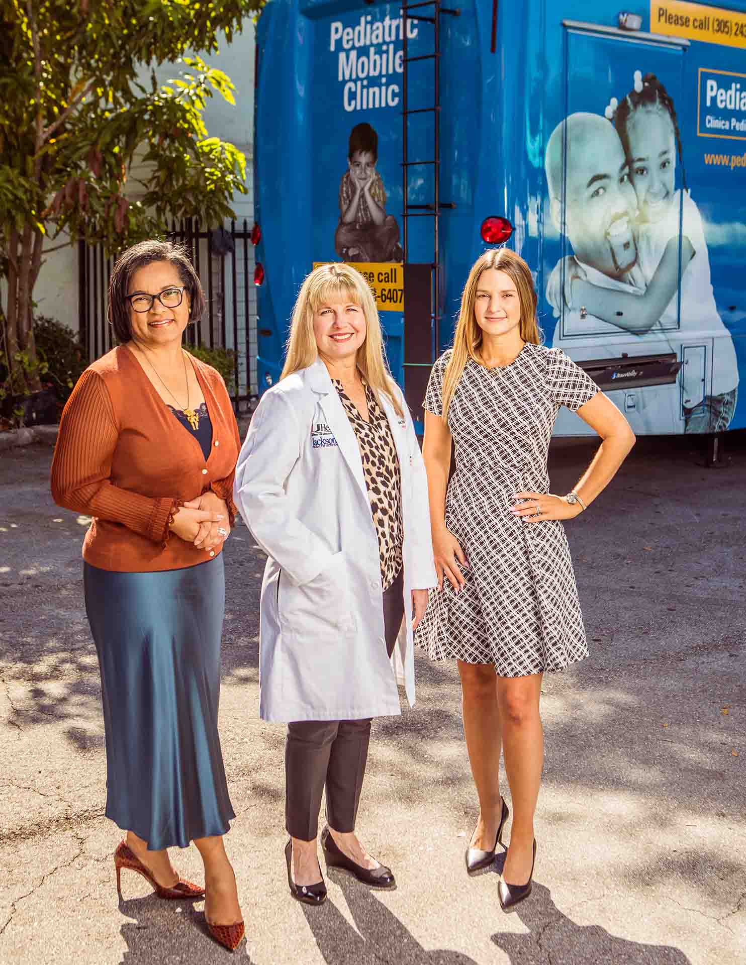 Women pose for photo in front of Pediatric Mobile Clinic