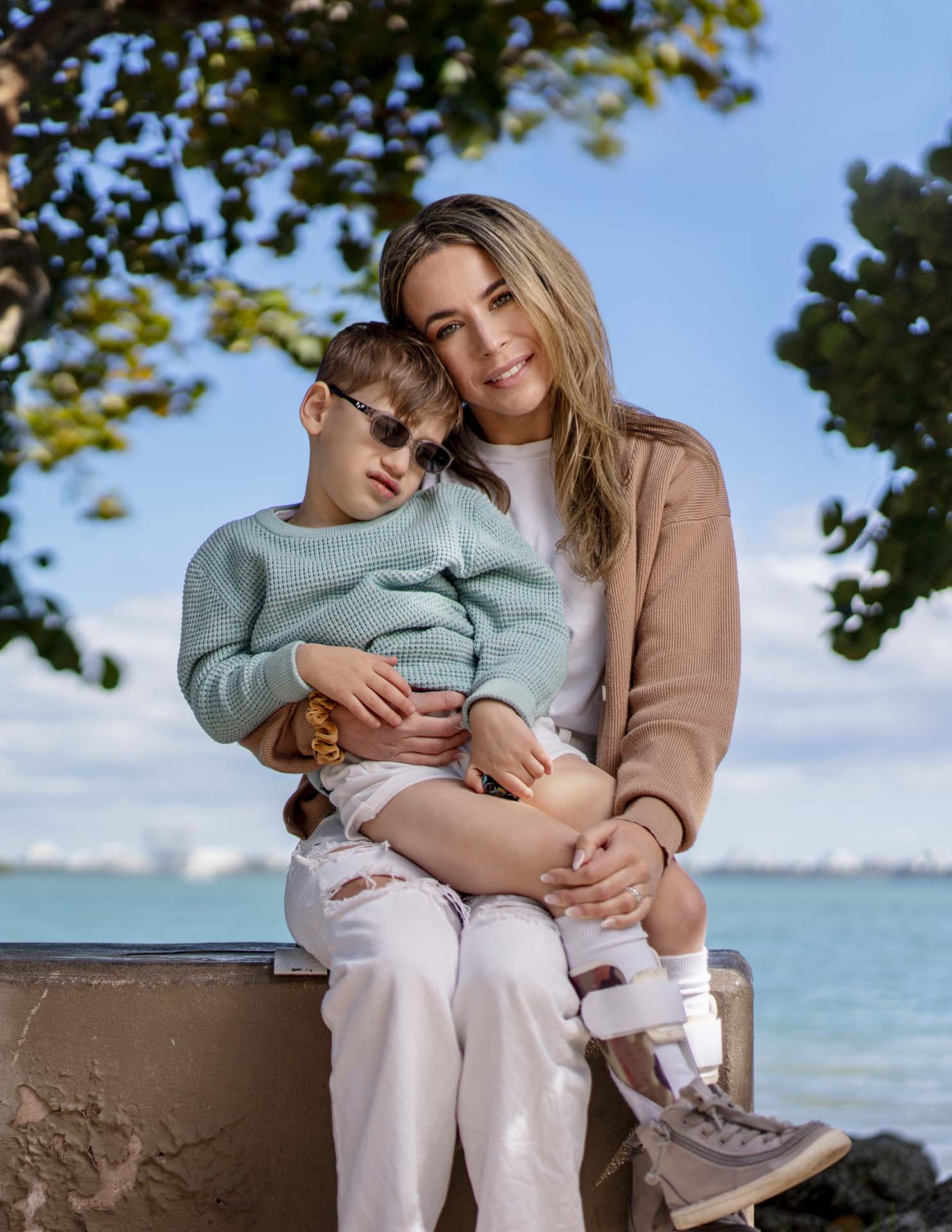 Woman poses for a photo with her son at the beach