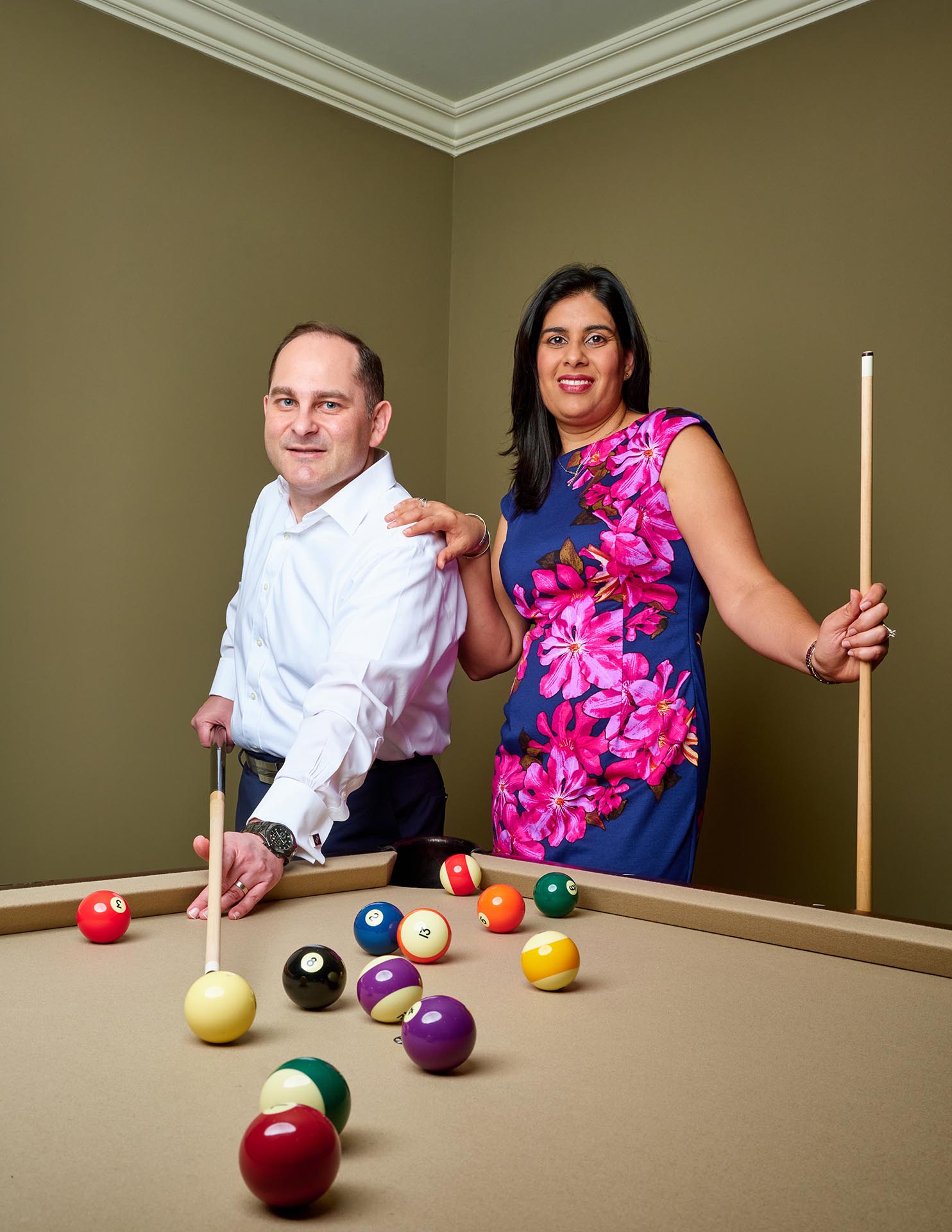 Couple poses for a photo at their billiards table