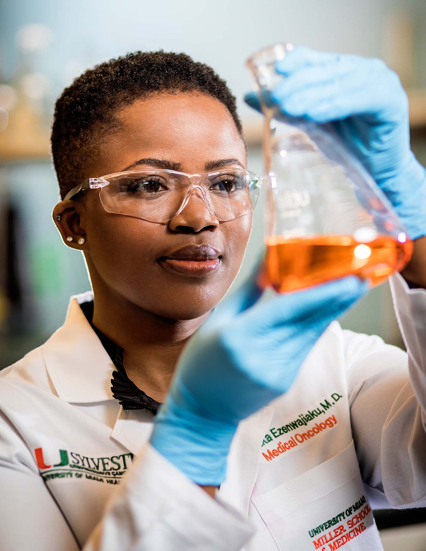 Woman examines a beaker with some orange fluid in it