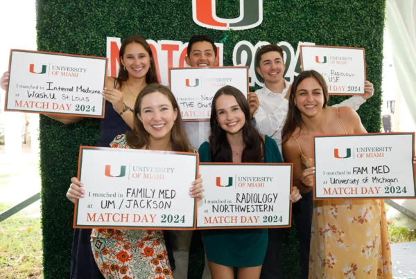 group of recent medical student graduates pose with signs