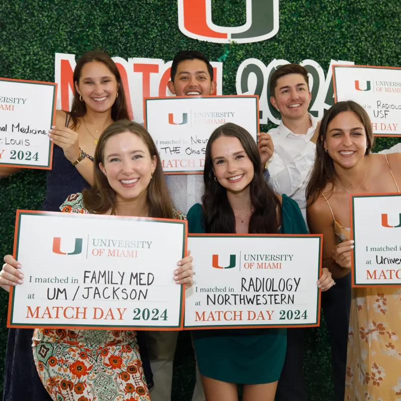 group of recent medical student graduates pose with signs